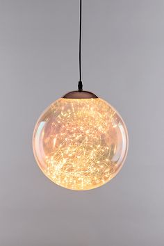 a glass ball hanging from a black cord on a gray background with lights in it