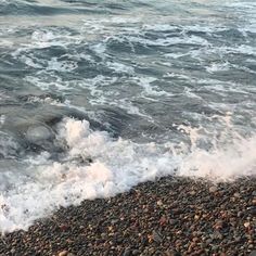 waves crashing onto the beach with rocks and pebbles