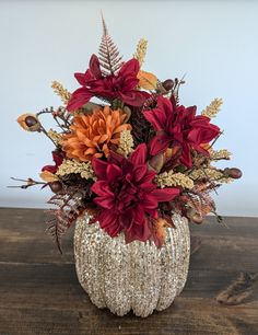 a vase filled with lots of flowers on top of a wooden table