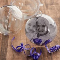 a glass ornament with a purple ribbon around it on a table next to a bowl