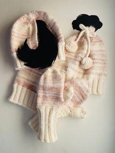 two knitted sweaters and a hat on a white surface with a black object in the middle