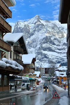 the mountains are covered in snow as people walk down the street