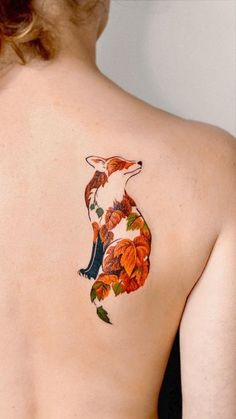 the back of a woman's shoulder with a fox and leaves tattoo on it