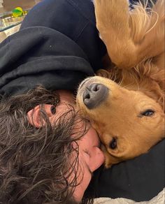 a man laying on top of a bed next to a dog with his head on the pillow