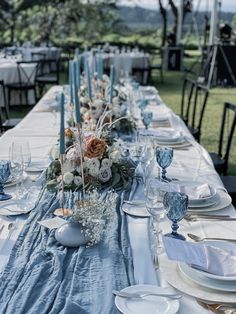 the table is set with blue and white plates, silverware, and centerpieces