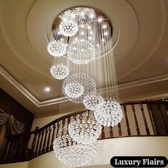 a chandelier hanging from the ceiling in a room with stairs and railings