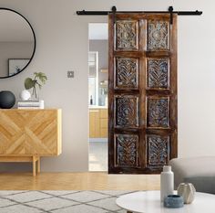 a living room filled with furniture and a large wooden door in front of a mirror