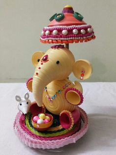 an elephant figurine sitting on top of a bowl with a lamp above it