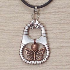 a necklace with a butterfly on it and a bead hanging from the front, attached to a leather cord