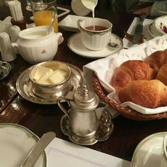 croissants and butter are in a basket on a table with other dishes