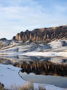 the mountains are covered in snow near a lake