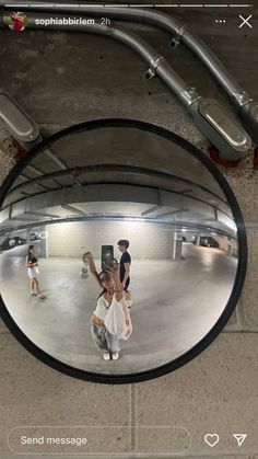 the reflection of two people in a round mirror, with one person taking a selfie