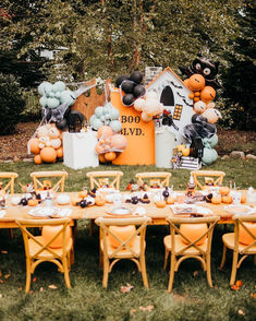 an outdoor halloween party with balloons and decorations on the lawn, including a table set for two