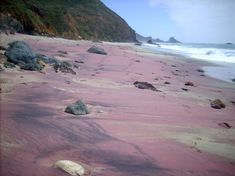 the beach is covered in pink sand and rocks