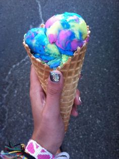 a person holding an ice cream cone with colorful toppings