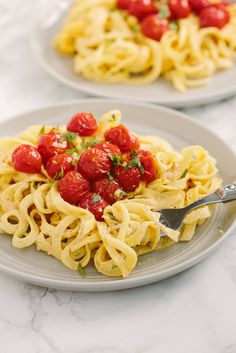 two plates with pasta and tomatoes on them