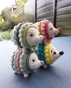 three small crocheted hedgehogs sitting next to each other on a table