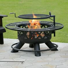 a fire pit sitting on top of a stone patio next to two black tables and chairs