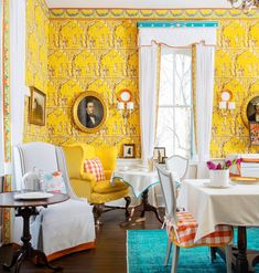 a dining room with yellow wallpaper and white table cloths on the floor, two chairs in front of a window