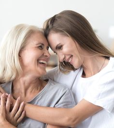 two women hugging each other while sitting on a couch