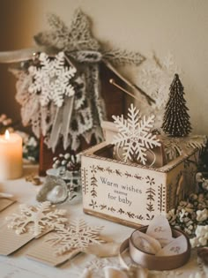 a box with snowflakes on it sitting next to other decorations and candles in front of a christmas tree