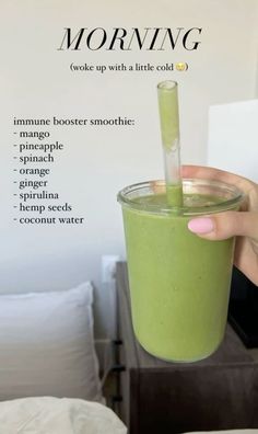 a woman holding a green smoothie in her hand