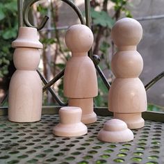 three wooden toy figures sitting on top of a metal table