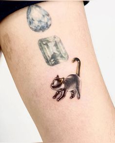 a small cat tattoo on the side of a woman's leg, with diamonds in the background