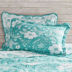 two pillows on top of a bed next to a headboard with wood planks in the background