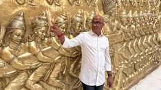 a man standing in front of a golden wall with carvings on it's sides