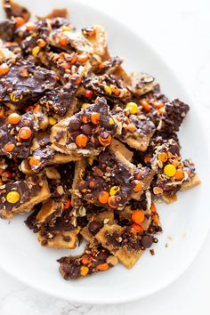 a white plate topped with lots of chocolate and candy covered cracker cookies on top of it