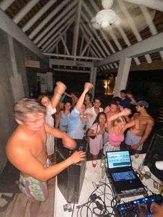 a group of people are dancing in front of laptops and dj's at a party