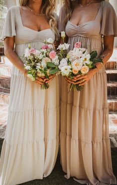 two beautiful women standing next to each other holding bouquets of flowers in their hands