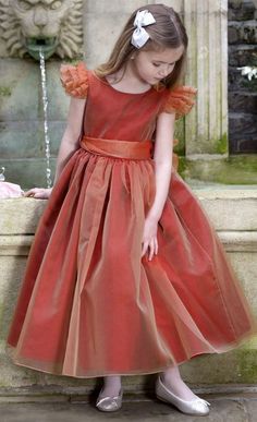 Love! NICKI MACFARLANEBurnt Red Silk Organza Ballerina 'Francesca' Dress. In a stunning shade of 'Firecracker' burnt orange/red, this full and voluminous dress has a fitted bodice with organza ruffle capped sleeves. The ballerina length skirt is gathered and full, with a layer of silk chiffon underneath and further underskirts of stiff tulle petticoats which add volume. Princess Frocks For Kids, Princess Frocks, Voluminous Dress, Frocks For Babies, The Ballerina