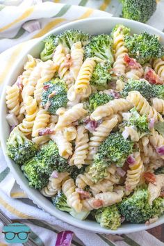 a white bowl filled with pasta and broccoli on top of a striped table cloth