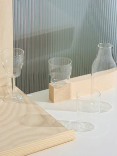 three empty wine glasses sitting on top of a table next to a wooden cutting board