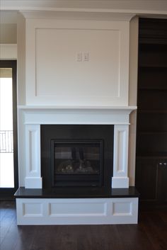 an empty fireplace in a living room with hard wood flooring and white painted walls