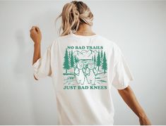 Discover the perfect t-shirt for nature lovers and hiking enthusiasts! This unique t-shirt features an inspiring message that reads No Bad Trails, Just Bad Knees, making it a must-have for those who enjoy exploring the great outdoors. Whether you're hitting the trails, climbing mountains, or simply taking a leisurely stroll in nature, this shirt is sure to be your go-to choice. Made with high-quality material and designed for comfort, this t-shirt is the ideal companion for your next outdoor adv Funny Print T-shirt For Outdoor Activities, White Pre-shrunk T-shirt For Hiking, Funny Print Short Sleeve Tops, Funny Print Short Sleeve Tops For Outdoor Activities, White Graphic Tee For Outdoor Activities, White Graphic Print T-shirt For Hiking, Climbing Mountains, Bad Knees, Inspiring Message