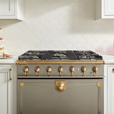 a stove top oven sitting inside of a kitchen next to white cupboards and counter tops