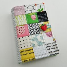 a small notebook covered in patchwork and fabric with a strawberry on the front cover