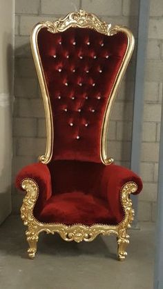 a red and gold chair sitting in front of a brick wall