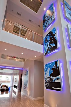 the interior of a modern house with paintings on the wall and stairs leading up to the second floor