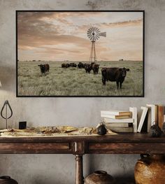 cows grazing in an open field with a windmill in the background framed on a wall