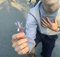 a man holding a small purple flower in his right hand