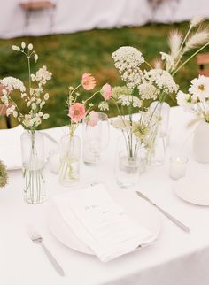 the table is set with flowers in vases