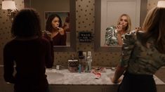 two women standing in front of a bathroom mirror brushing their teeth