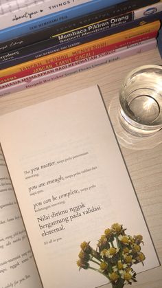 an open book sitting on top of a table next to a cup and some books