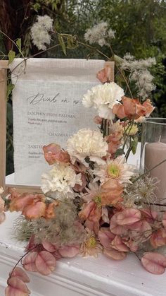 an arrangement of flowers and candles on a mantle