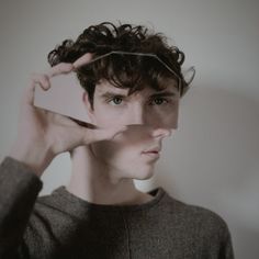 a young man is holding his hair in front of his face