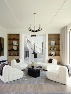 a living room filled with white furniture and a chandelier hanging from the ceiling